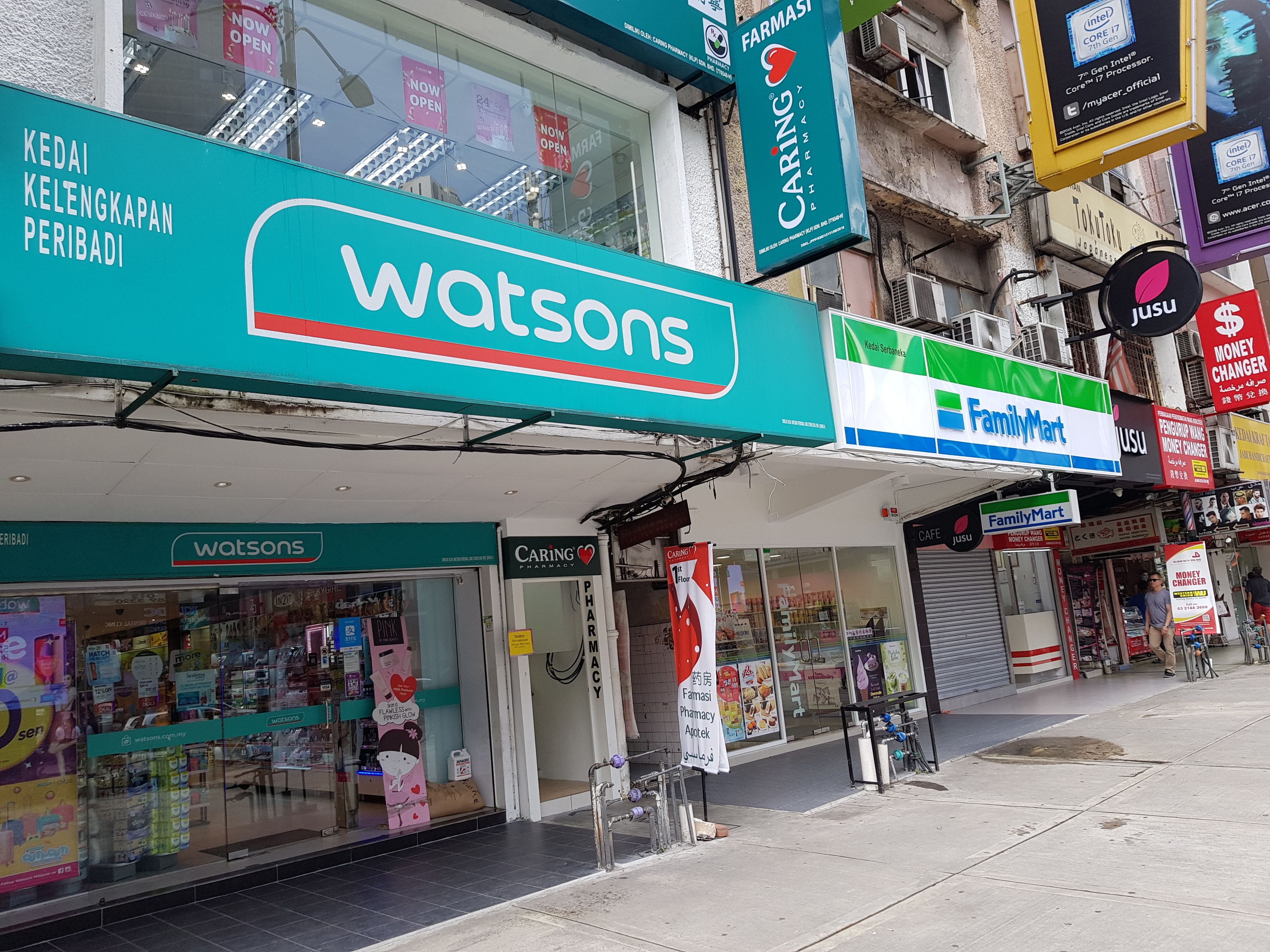 A storefront with a 'Watsons' sign, a 'Caring Pharmacy' sign, and a 'FamilyMart' sign.