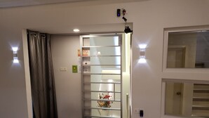 Entrada de hotel con puerta de vidrio, un escalón y una lámpara en la pared.