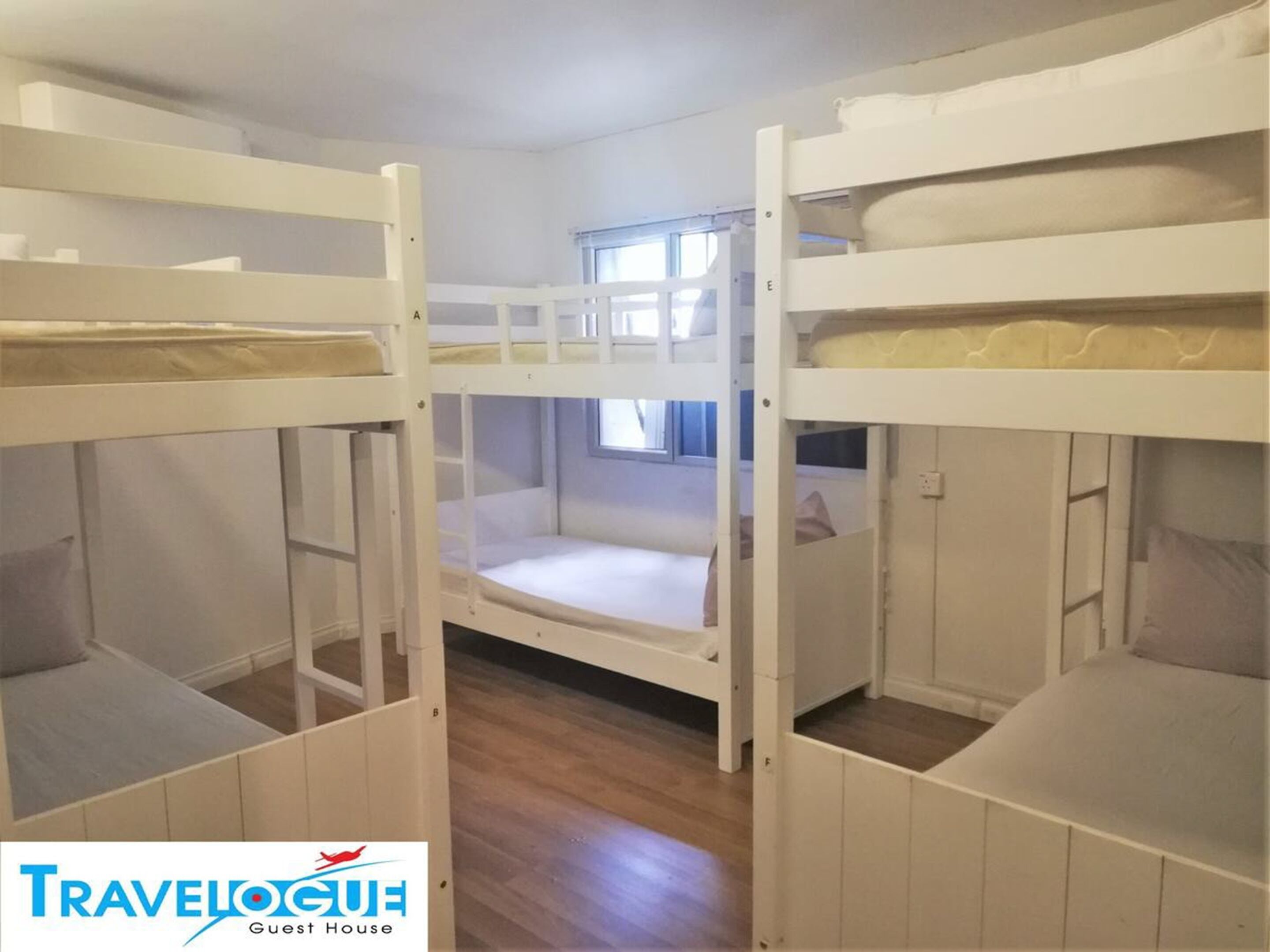 A guest room with bunk beds, a window, and a wooden floor.