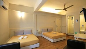 Habitación de hotel con dos camas, un ventilador de techo, una mesita pequeña y una silla.