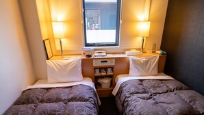 A small hotel room with two beds, a window, a desk with a telephone, and a shelf with toiletries. - AZ Inn Handa Inter (Handa)