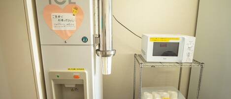 A medical facility with an 'ICE' sign, a water dispenser, and a microwave on a shelf.