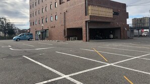 A parking lot with a multi-story building in the background. - AZ Inn Handa Inter (Handa)
