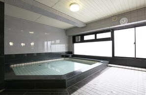 A large indoor swimming pool with a tiled floor and walls, a clock on the wall, and a window with blinds. - AZ Inn Handa Inter (Handa)