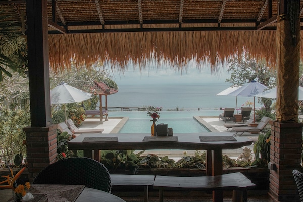 Una piscina al aire libre, sombrillas, sillones reclinables de piscina