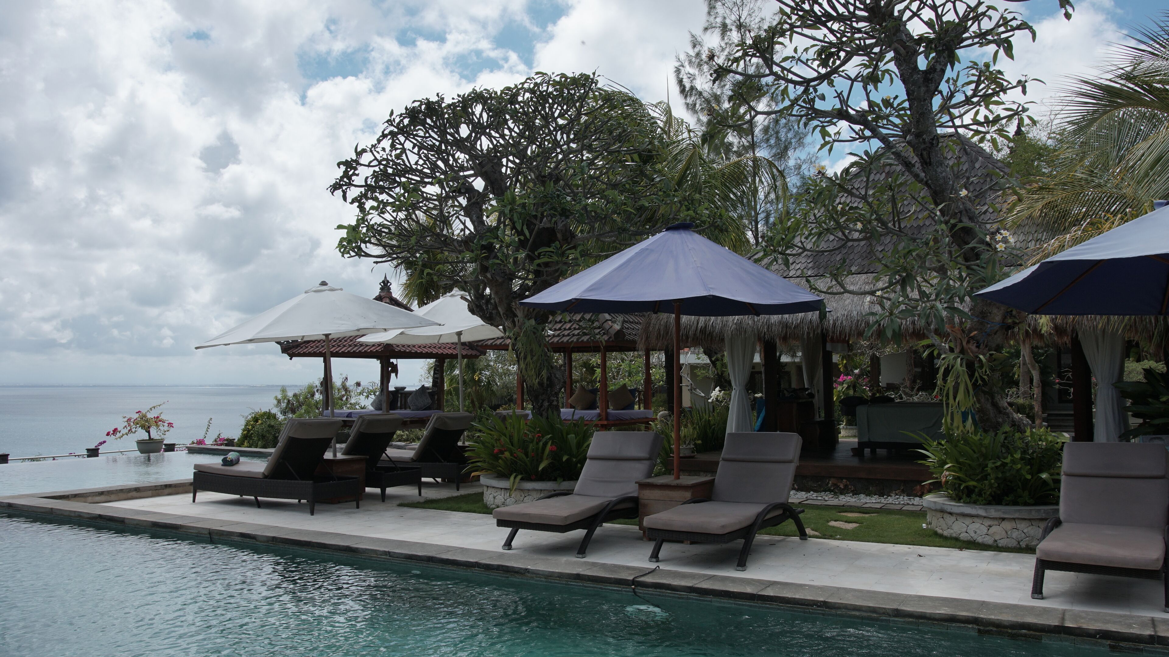 Una piscina al aire libre, sombrillas, sillones reclinables de piscina