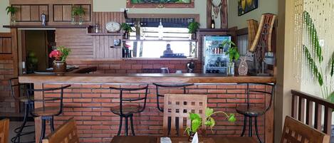 Un restaurante acogedor con mostrador de ladrillo, sillas de madera y una variedad de plantas y adornos.
