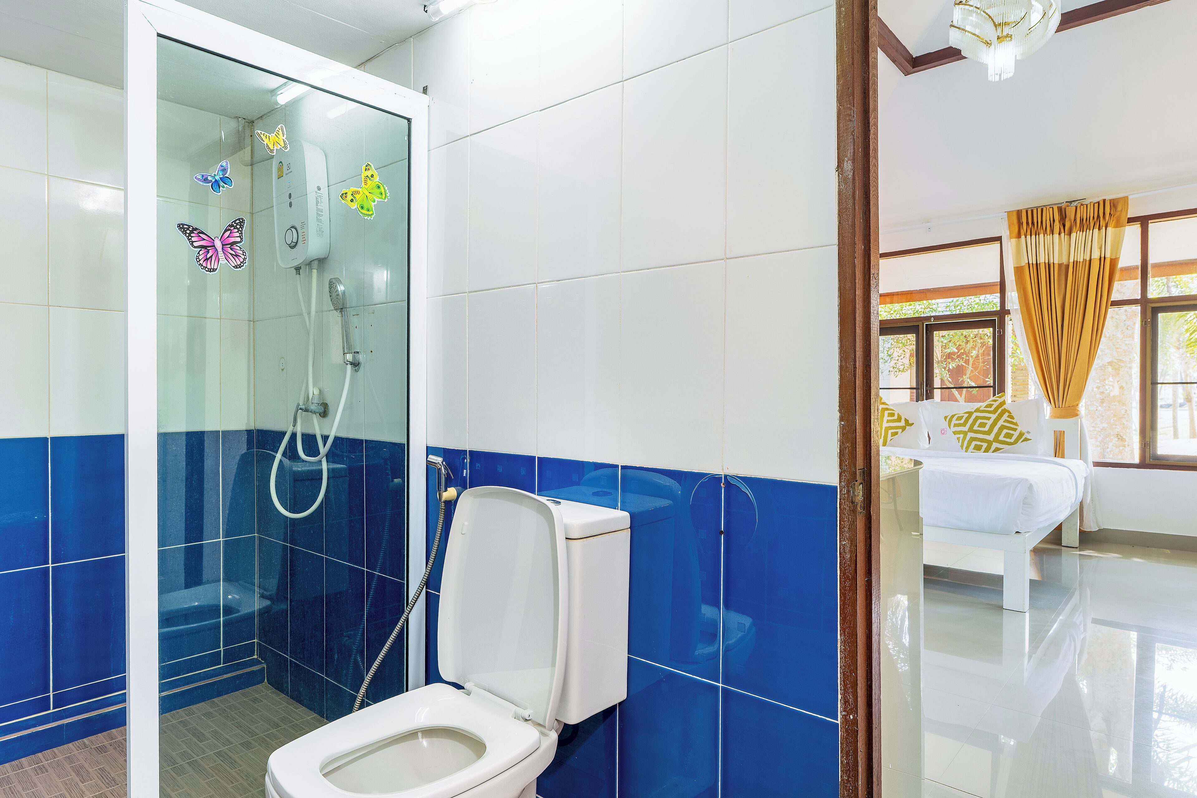 Une salle de bain avec une douche à parois de verre, des toilettes et un lit dans la pièce adjacente.