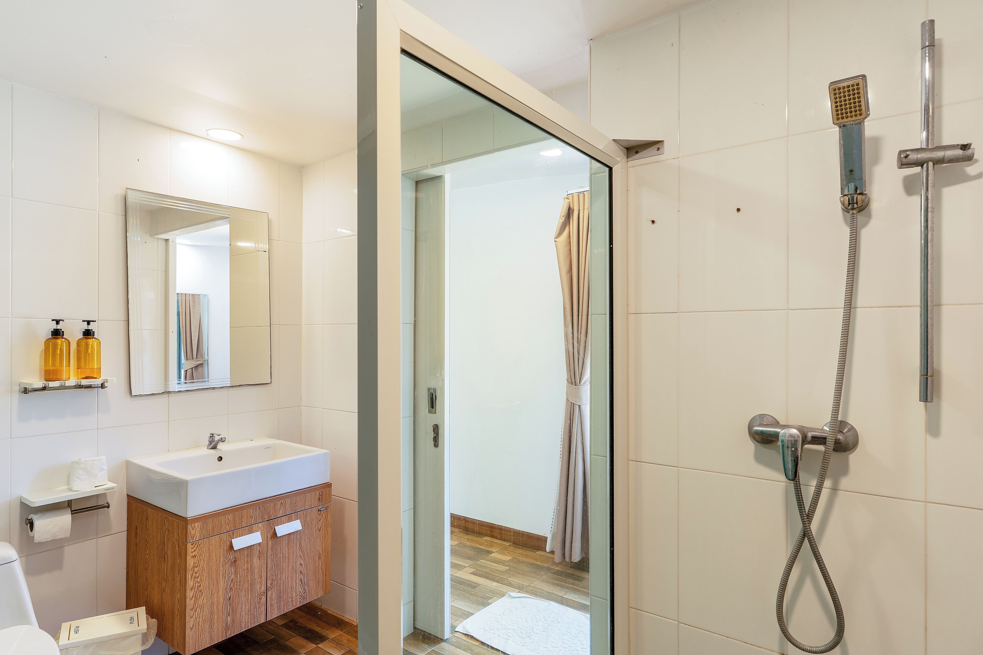 Une salle de bain moderne avec une douche à parois de verre, un lavabo blanc et des meubles en bois.