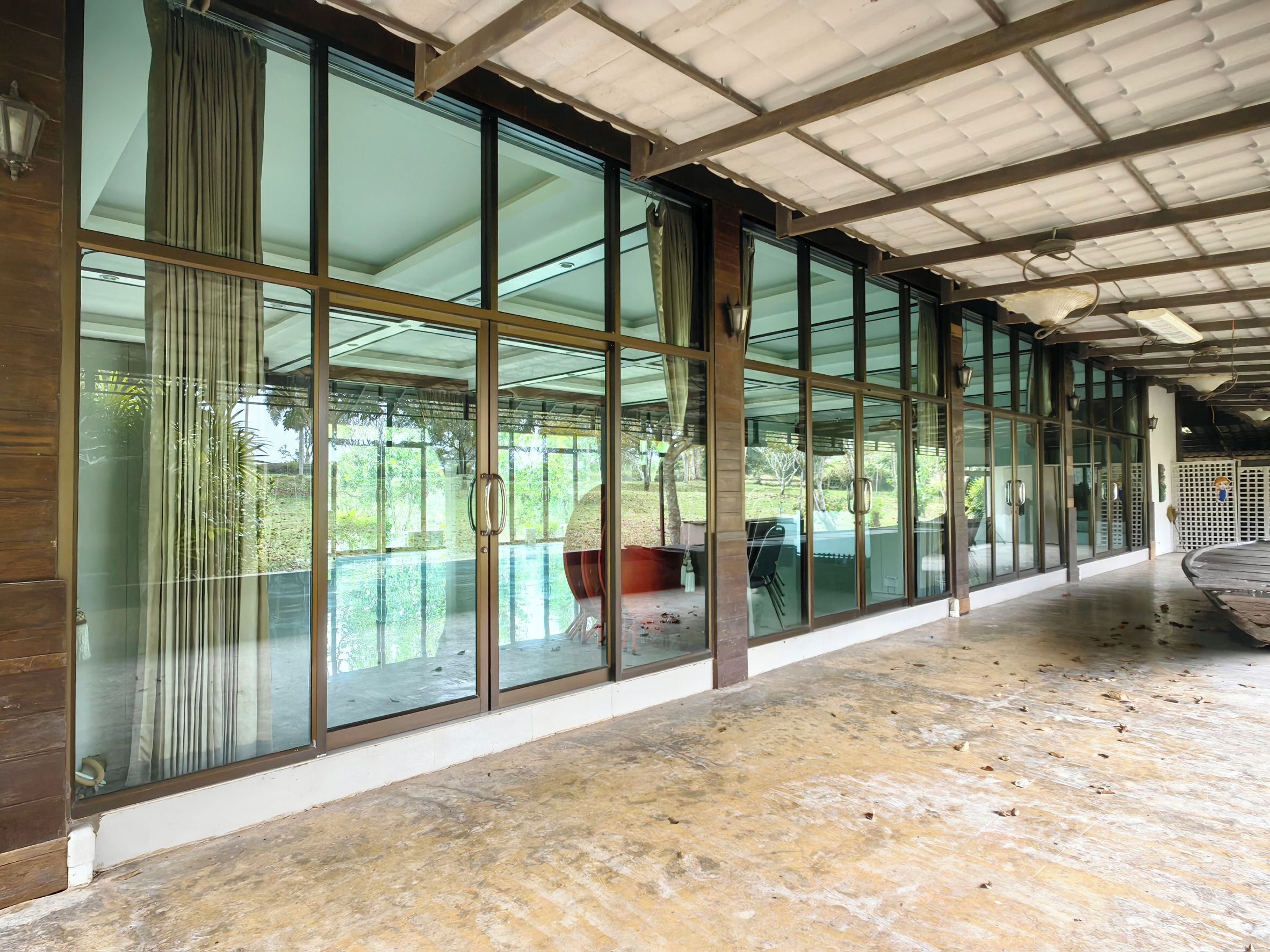 Un couloir doté de grandes fenêtres en verre, de lambris en bois et d’une structure de toit en métal.