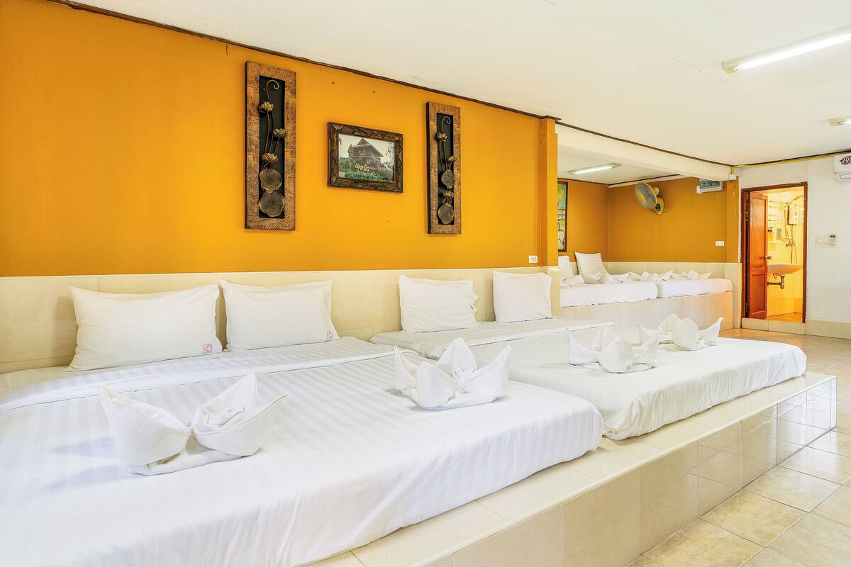 A hotel room with two beds, white bedding, and a yellow wall with framed pictures.