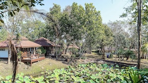 Ein friedlicher Garten mit Teich, Holzbauten und üppigem Grün.