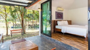 Ein Schlafzimmer mit einer großen Glasschiebetür, die zu einem Poolbereich führt, einer Holzbank und einem Bett mit weißer Bettwäsche.