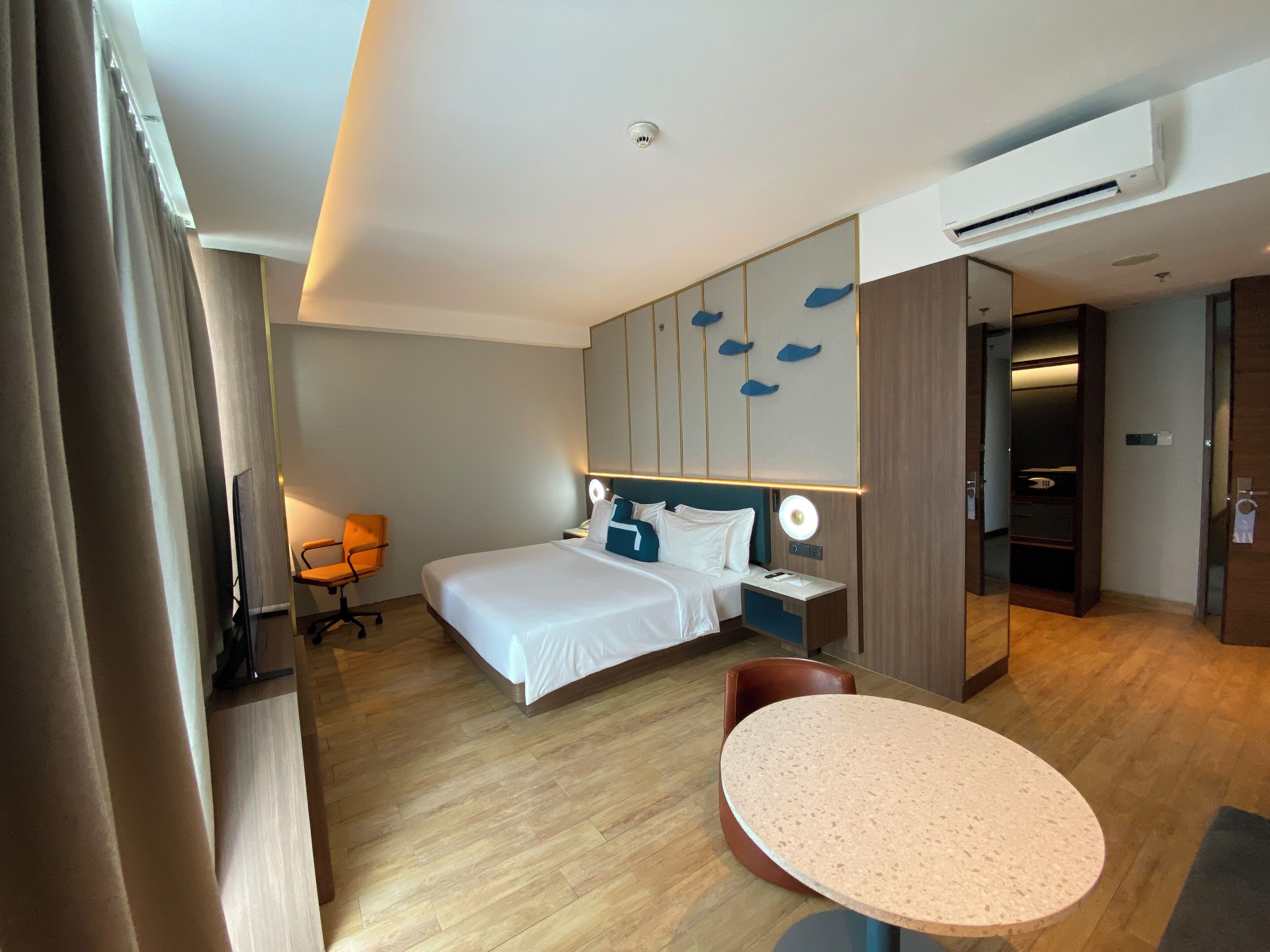 A hotel room with a bed, bedside table, chair, and a round table.