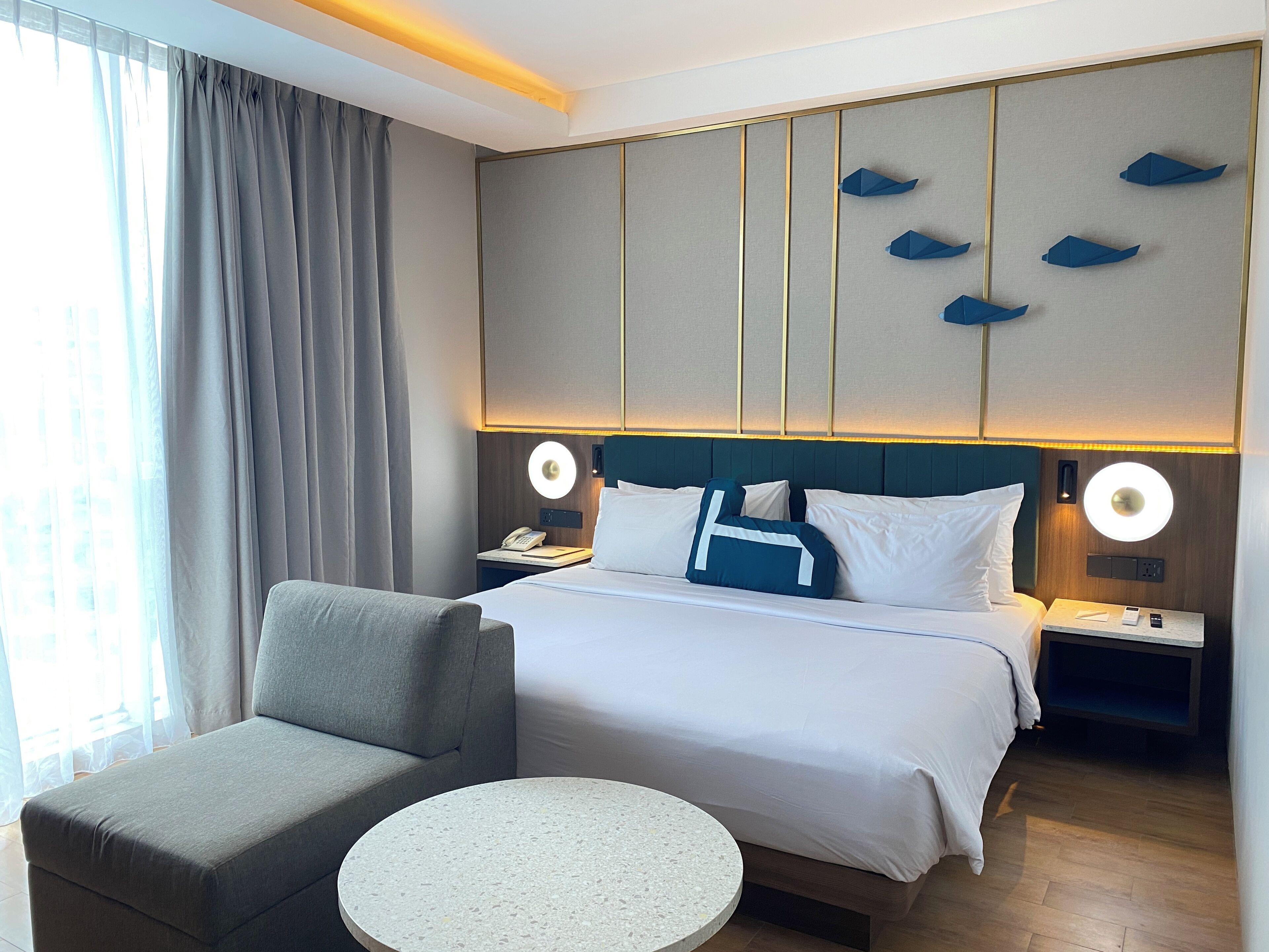 Una habitación de hotel con una cama, un sofá, una mesa redonda y vistas de la ciudad a través de la ventana.