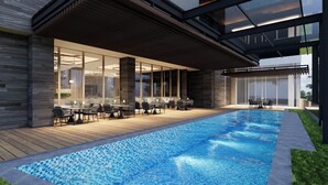 En pool med en trädeck, utomhusmöbler och en modern arkitektonisk design.