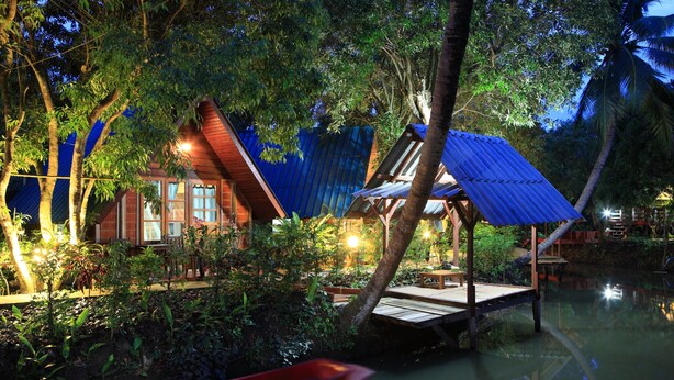 A wooden house with a blue roof, surrounded by lush greenery and a calm water body. - Banmaihom Amphawa (Amphawa)