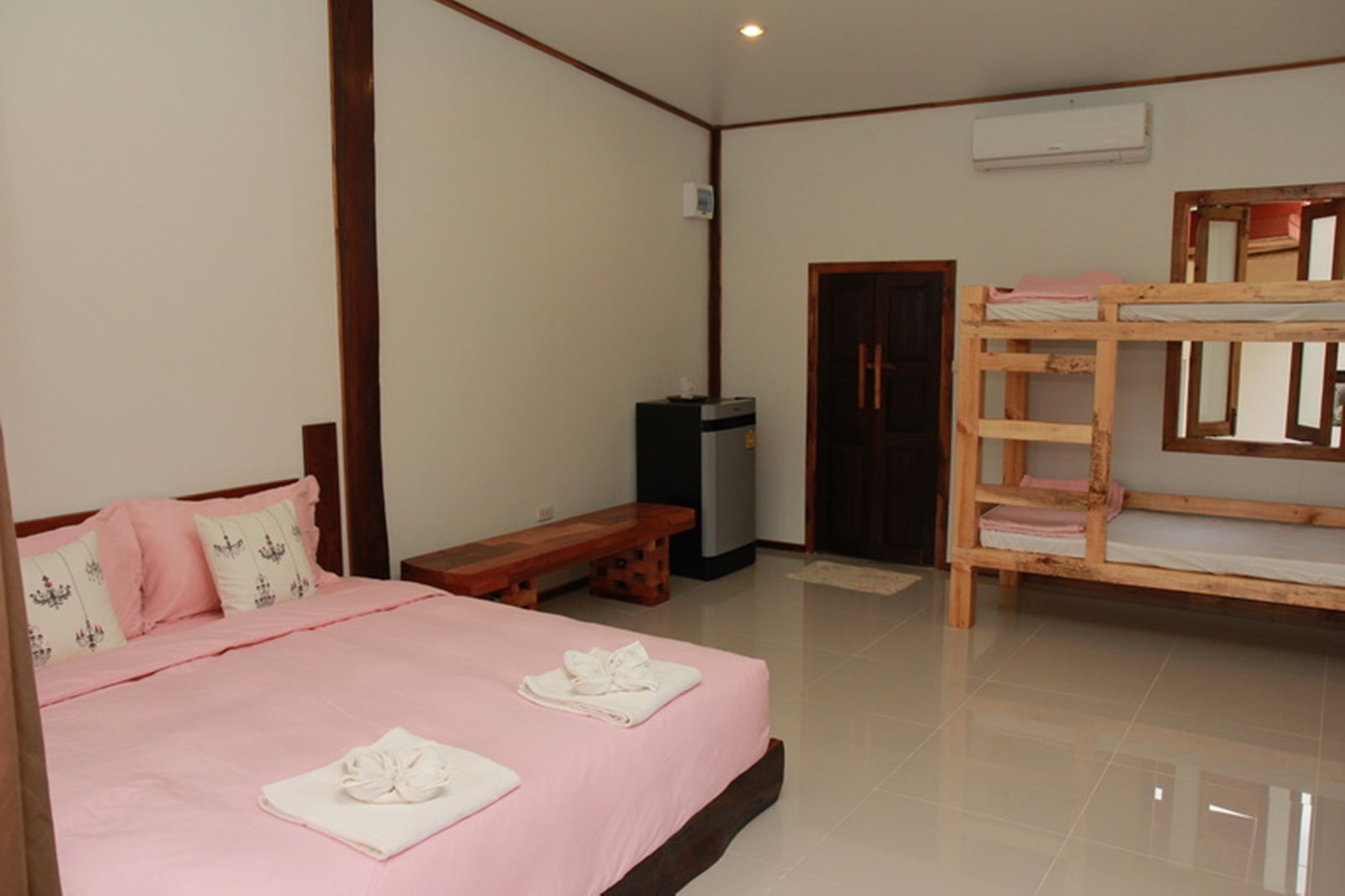 A bedroom with a single bed, a wooden bench, a bunk bed, and a small table.