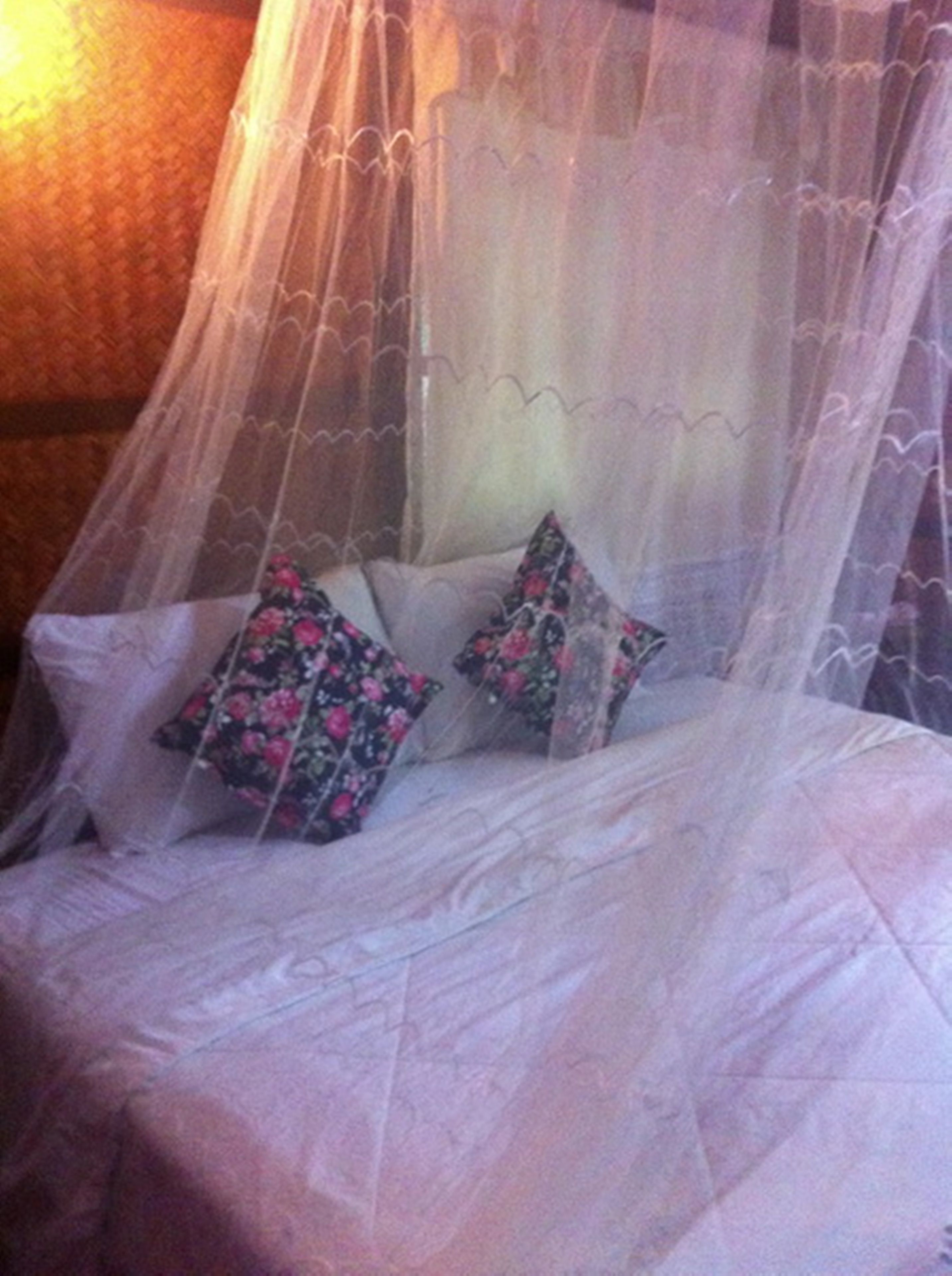 A bed with a canopy, pillows, and a textured wall.