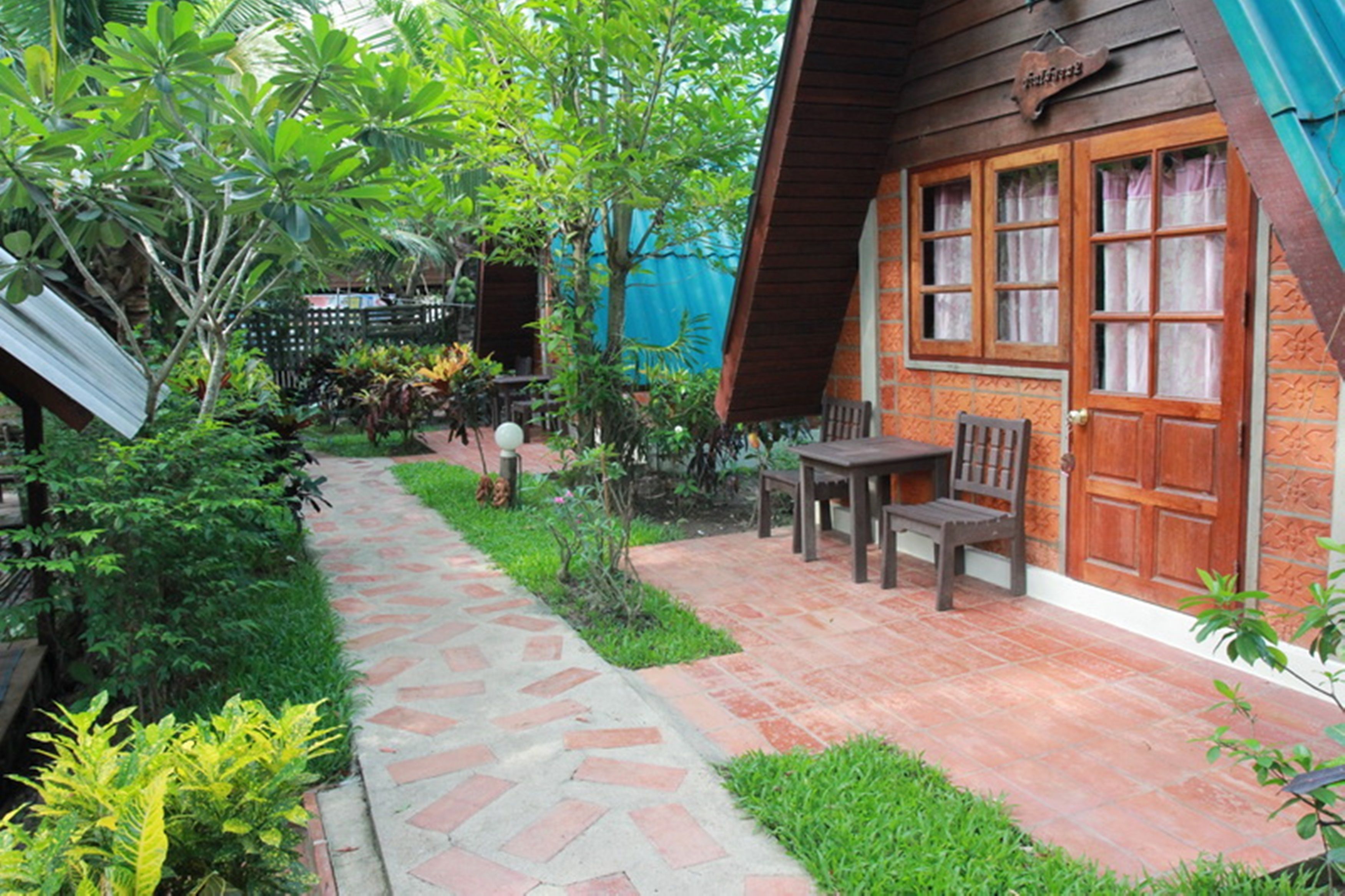 A courtyard with a stone pathway leading to a wooden building with a large door and windows.