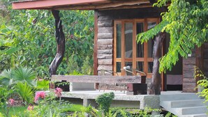 A rustic cabin with a stone exterior, large glass windows, and a wooden porch with seating. - Banmaihom Amphawa (Amphawa)