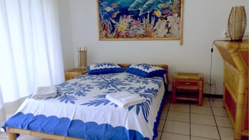 Ein Schlafzimmer mit Bett, Nachttisch, Lampe und einem Wandbild, das Meereslebewesen zeigt.