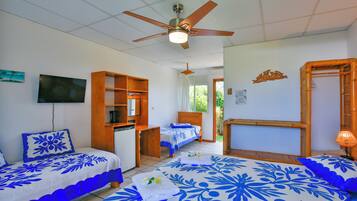 A hotel room with two beds, a ceiling fan, a TV, and a wooden shelf.