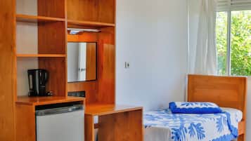 Une chambre avec deux lits, une petite kitchenette et une fenêtre avec des rideaux.