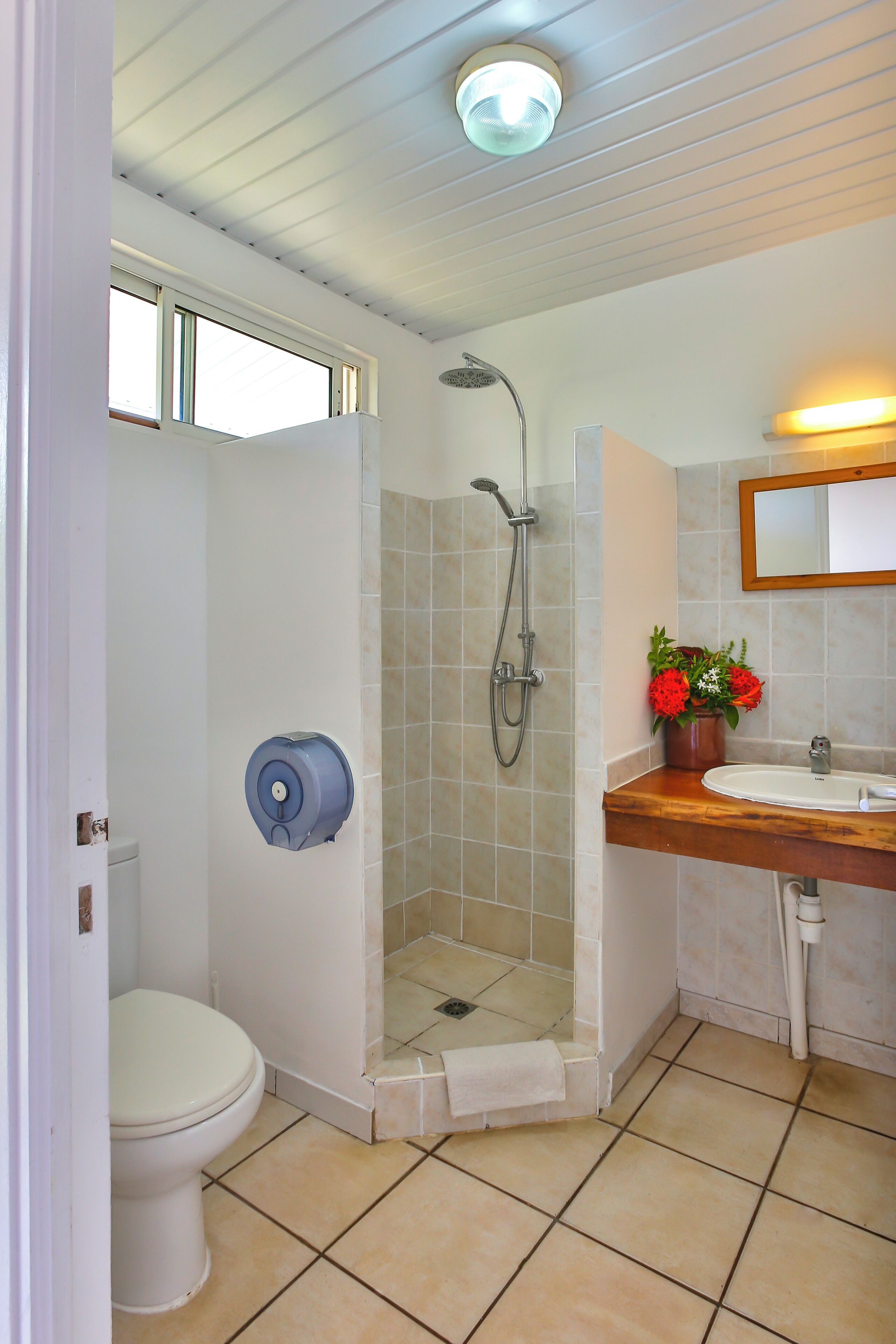 A bathroom with a toilet, shower, sink, and a mirror.