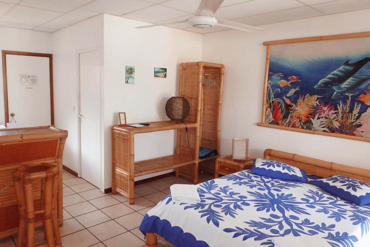Quarto com uma cama, escrivaninha, cadeira, prateleira e um quadro.