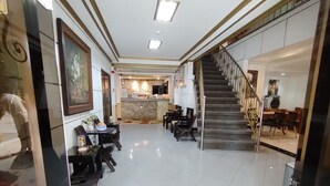 A hotel lobby with a staircase, a reception desk, and a dining area with chairs and tables. - Spring Plaza Hotel (Dasmarinas)