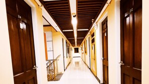 A long, narrow hallway with wooden doors on both sides, leading to a bright room at the end. - Spring Plaza Hotel (Dasmarinas)