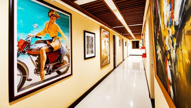 A hallway with framed artwork on the walls, a polished floor, and a wooden ceiling. - Spring Plaza Hotel (Dasmarinas)