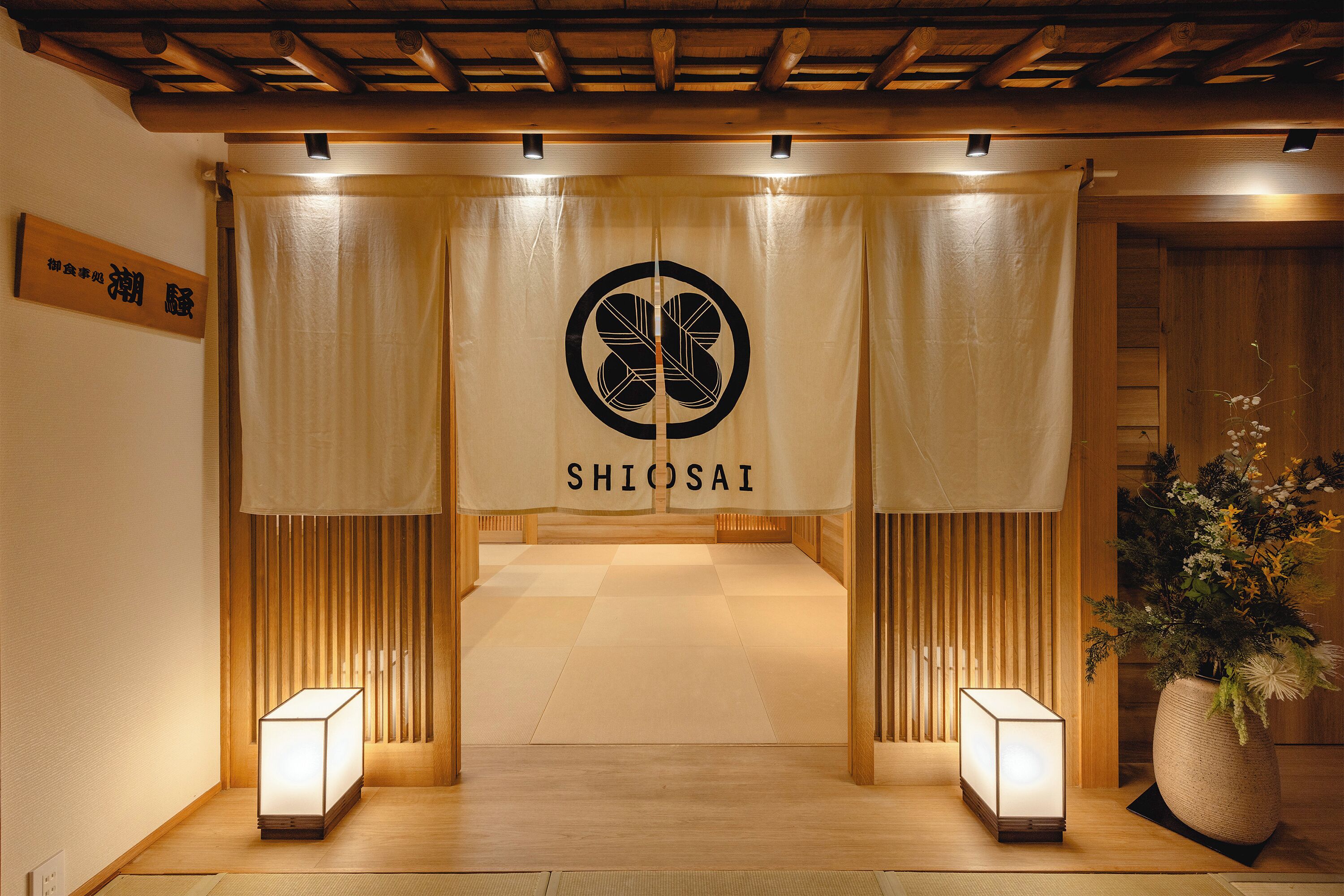 A traditional Japanese interior with a Shiosai logo, tatami flooring, and a wooden ceiling.