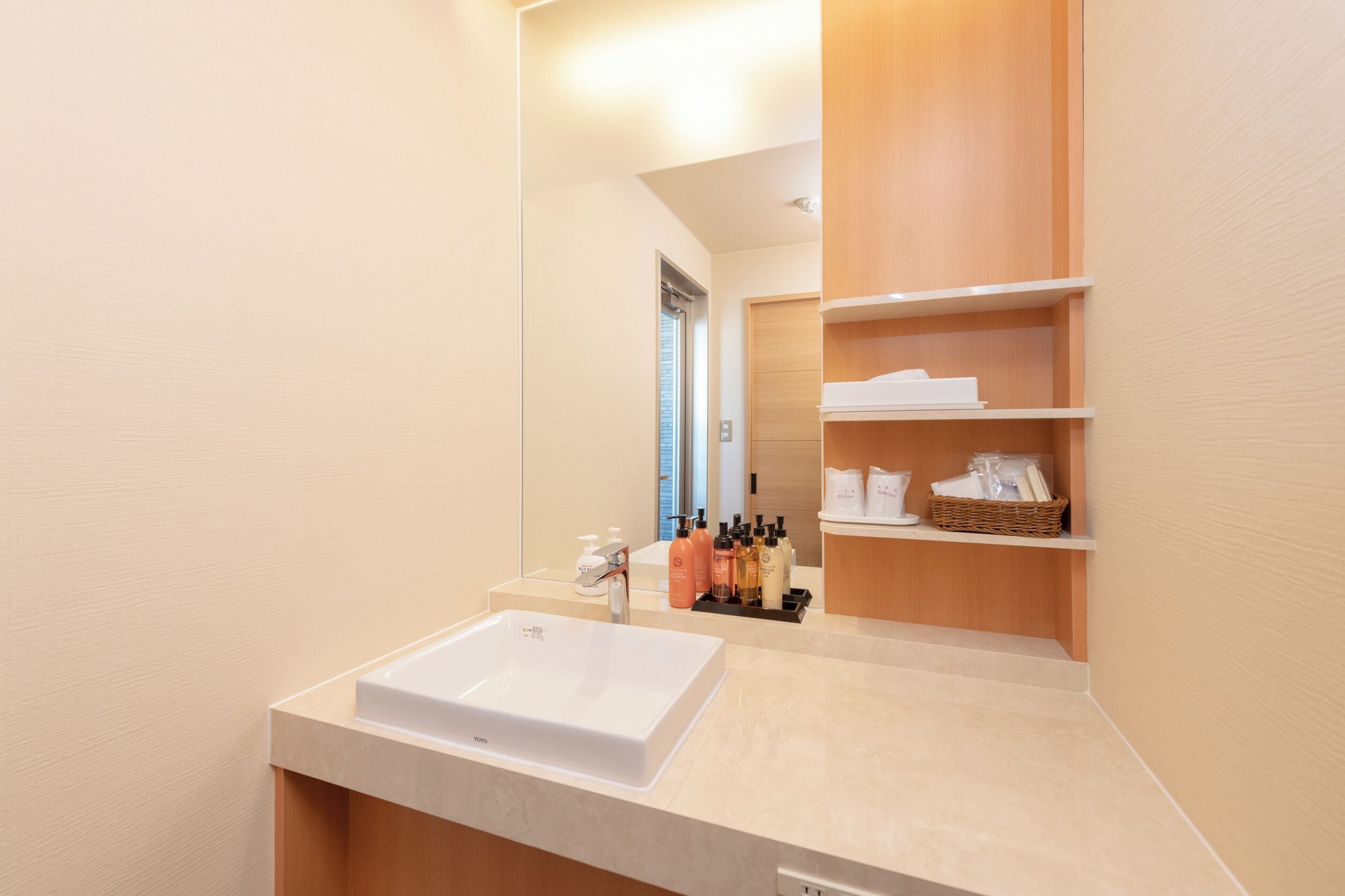 A modern bathroom with a large white sink, wooden shelves, and a mirror.