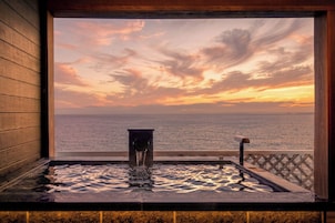 A hot tub with a view of the ocean and a sunset.