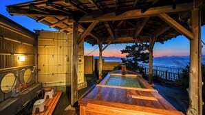 Ein Holzbad mit einer hölzernen Sitzbank, einer kleinen Toilette und Blick aufs Meer.