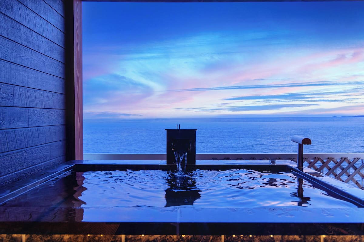 A spa area with a view of the sea, a water feature, and a wooden wall.
