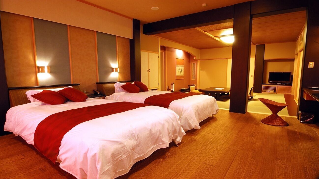A hotel room with two beds, a TV, and a seating area.