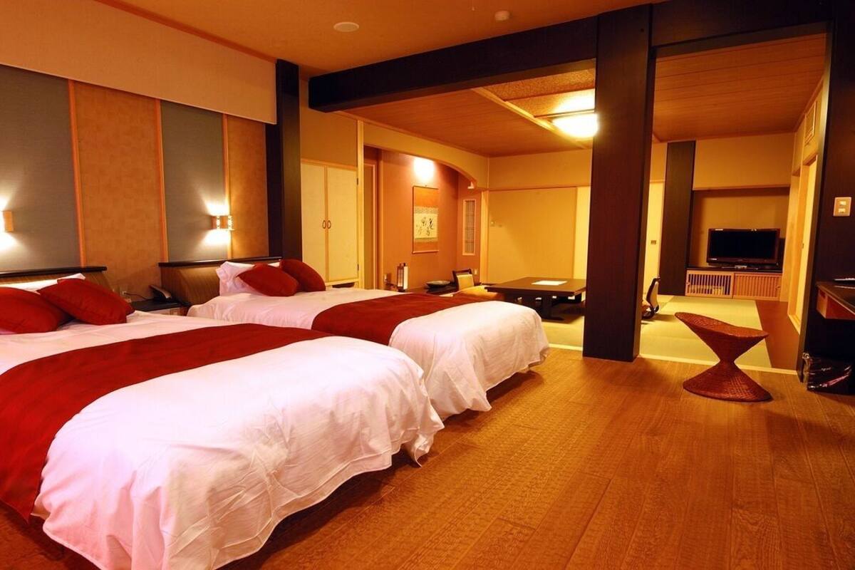 A hotel room with two beds, a TV, and a seating area.