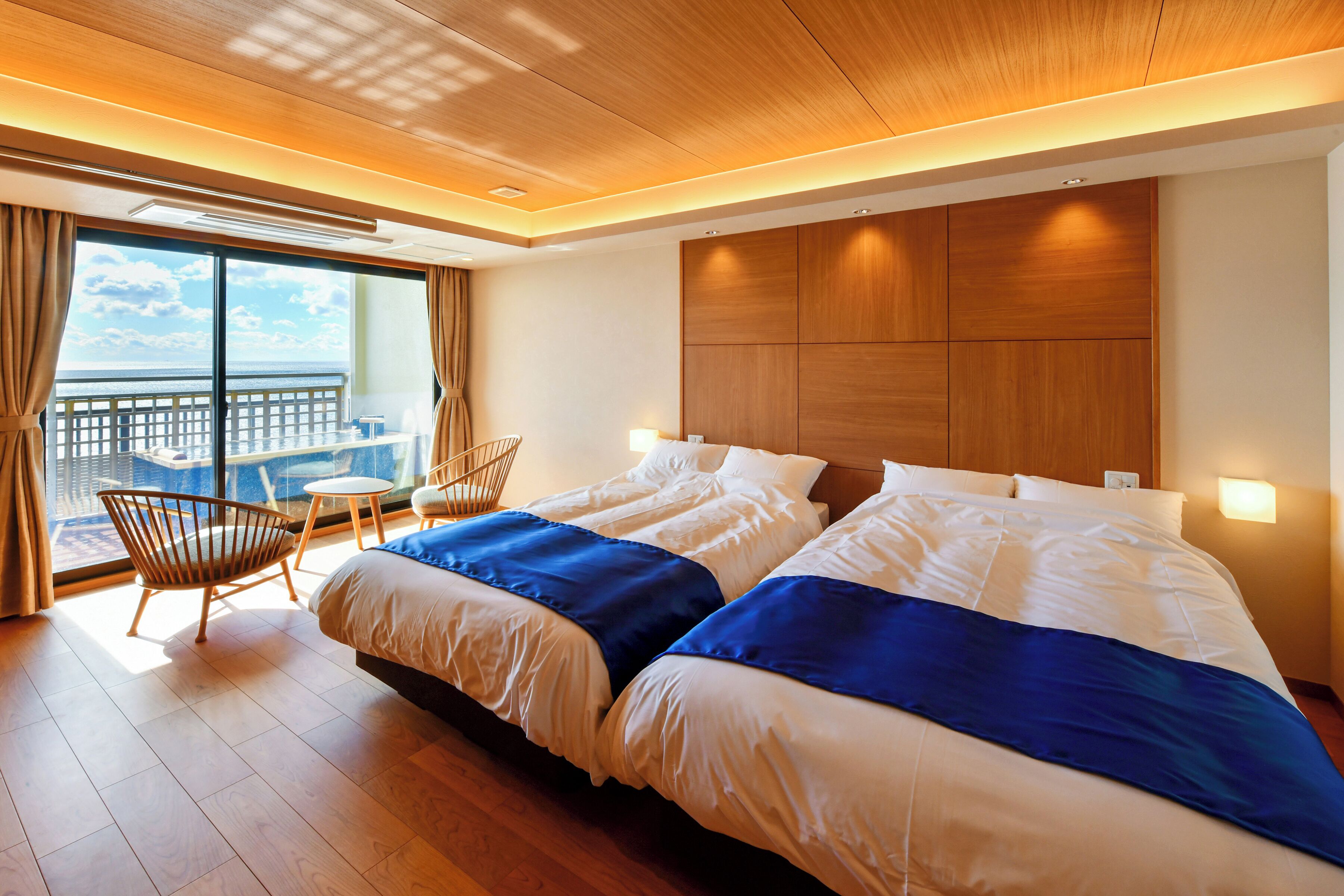 Una habitación de hotel moderna con una cama grande, un balcón con vistas y un techo de madera.