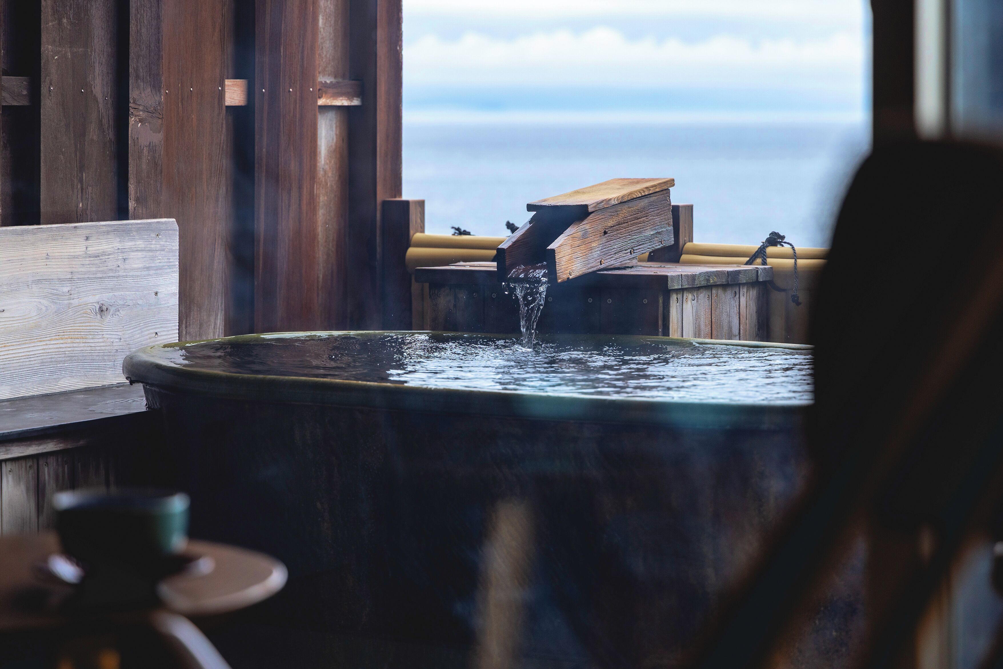 Une structure en bois agrémentée d’un élément aquatique, peut-être un jacuzzi ou un spa, offrant une vue sur le ciel et les nuages.
