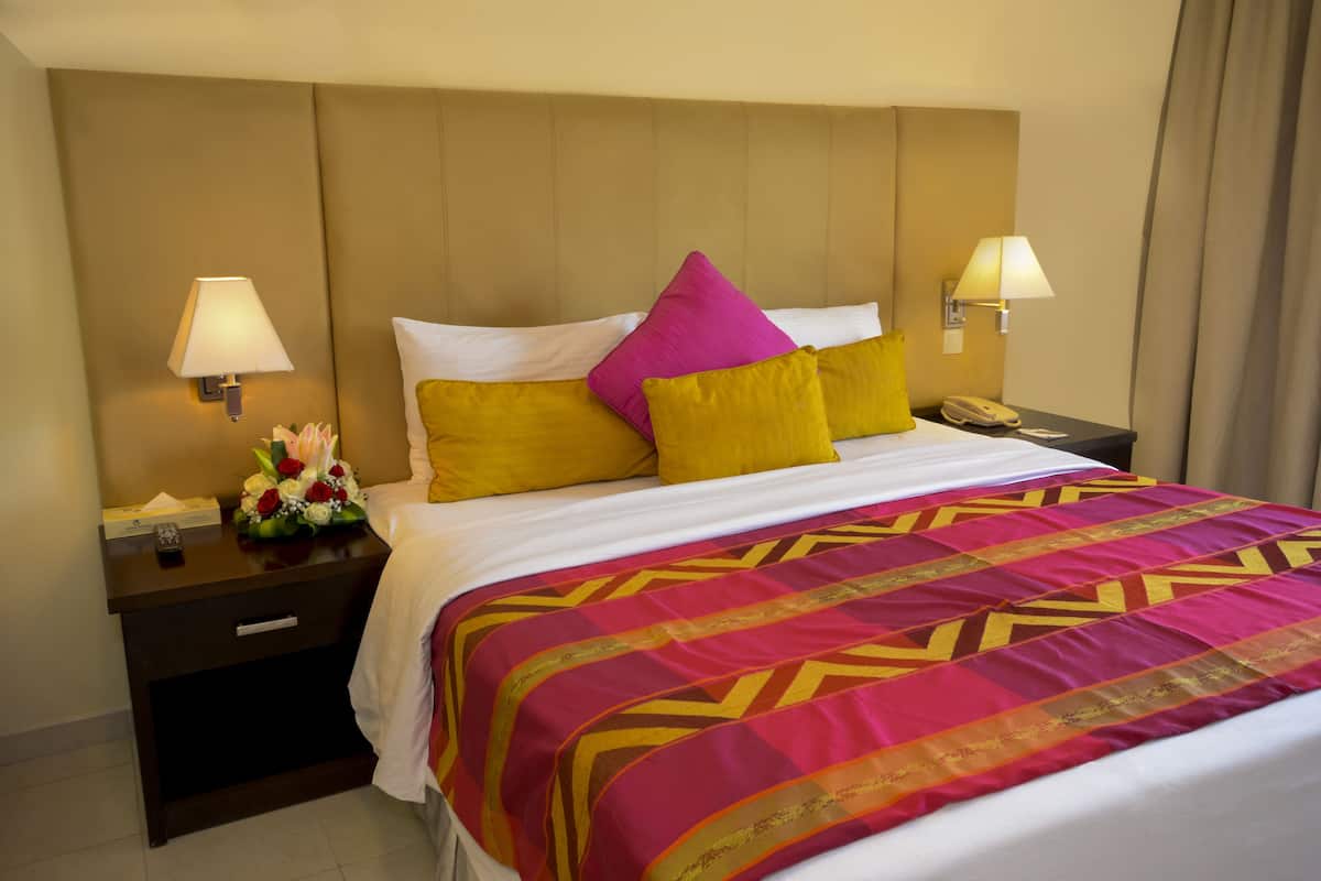 Une chambre d’hôtel avec un lit, deux tables de chevet, un téléphone et une lampe sur chaque table de chevet.