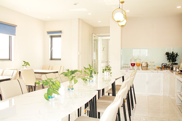 A modern dining area with a long table, chairs, and potted plants.