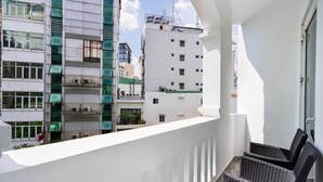 A balcony with wicker furniture, overlooking a cityscape with modern buildings. -  A&A Toronto Hotel (Ho Chi Minh City)