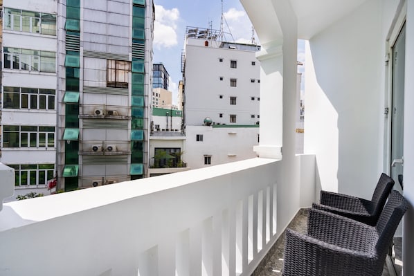 Un balcón con muebles de mimbre, con vistas a un paisaje urbano con edificios modernos.