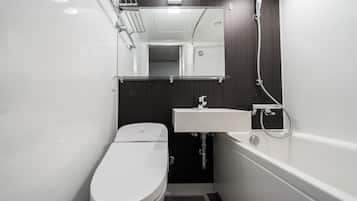 Een compacte, moderne badkamer met een wit toilet, een wastafel en een bad.