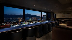 Un bar con vistas a la ciudad, diseño moderno y varios taburetes.