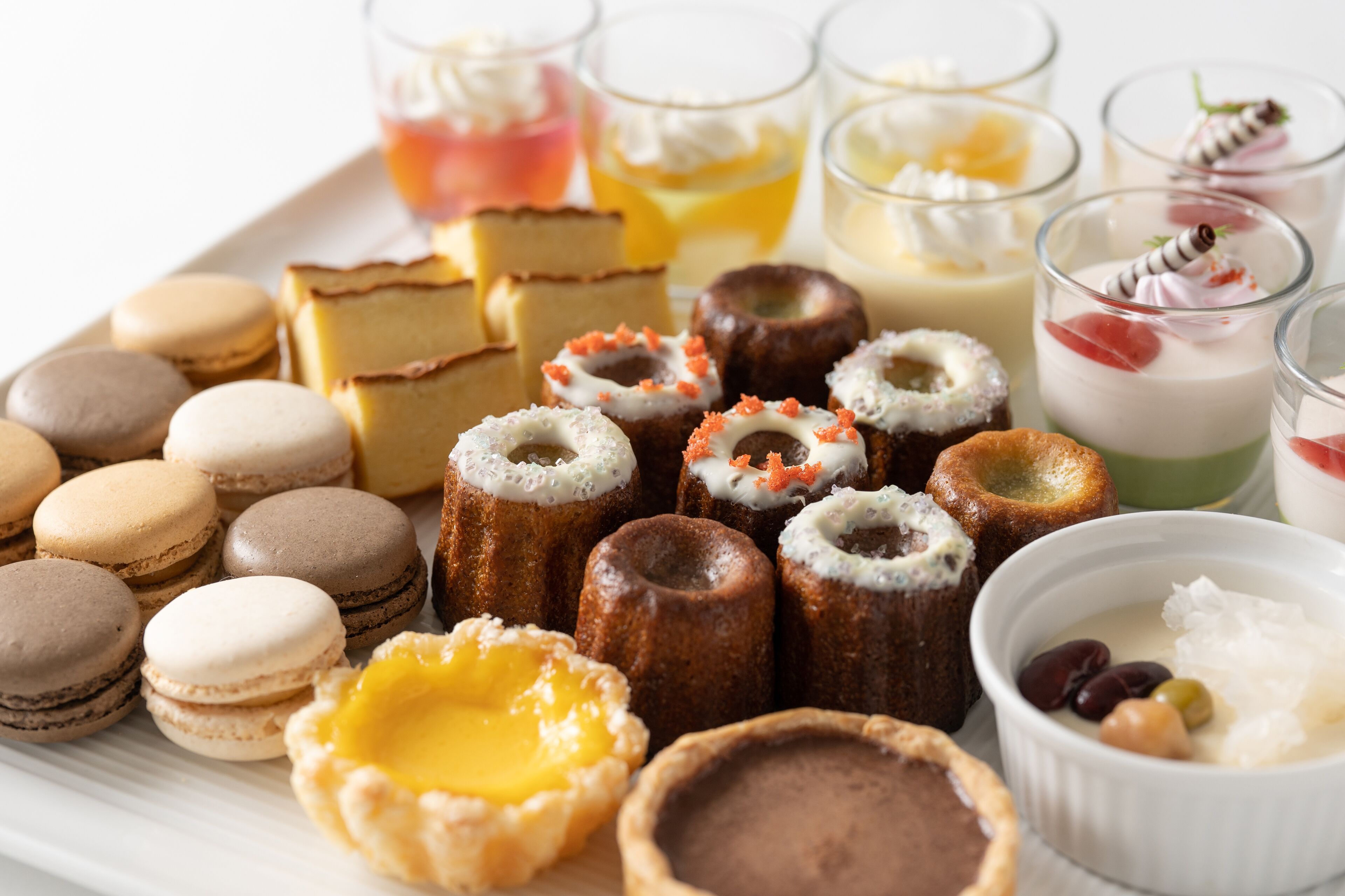 Una variedad de postres, entre ellos macarons, tartaletas y pequeños pasteles, dispuestos en una bandeja.