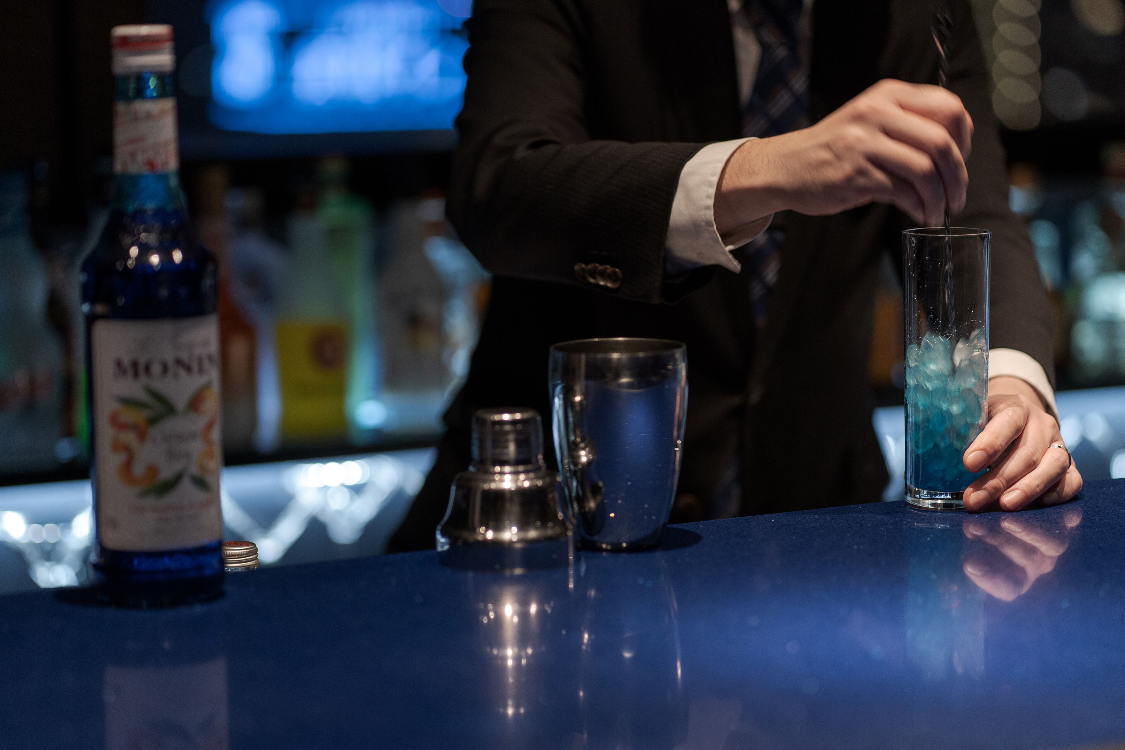 A bar setting with a bottle of MONTE, a cocktail shaker, and a tall glass with ice.